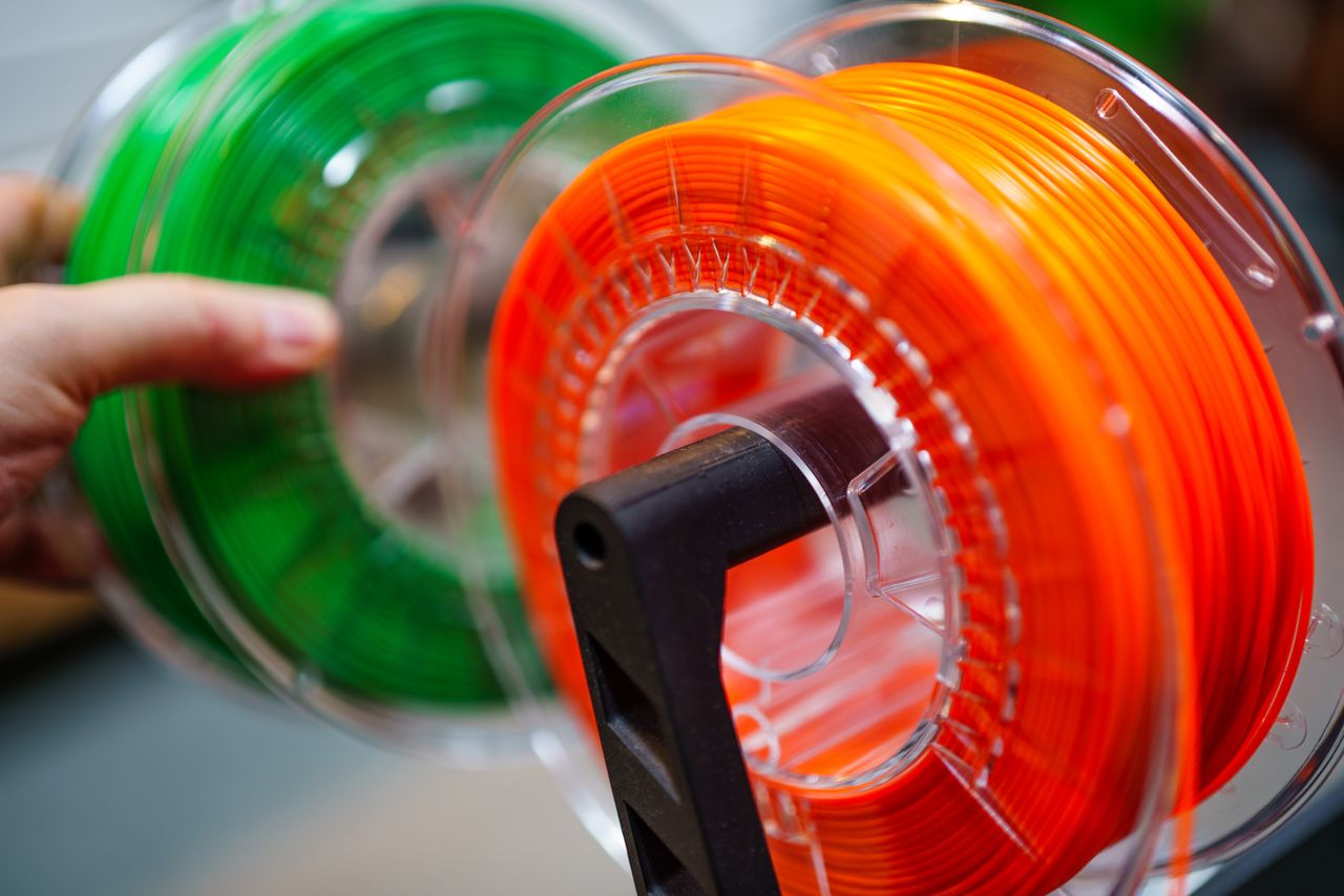 why-choose-us Vibrant orange and green 3D printer filament spools for innovative manufacturing uses.
